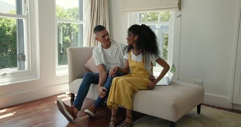 Diverse Couple Relaxing at Home with Laptop Nearby