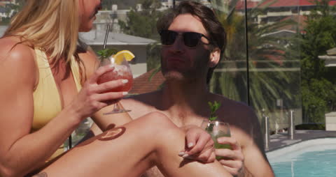 Couple Relaxing by Pool with Cocktails in Tropical Setting