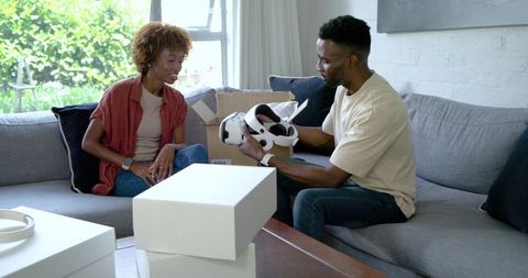 African american couple unboxing vr headset on modern living room sofa