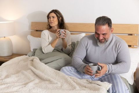 Cozy morning couple sharing coffee in bed, relaxed pajama intimacy and warm home comfort