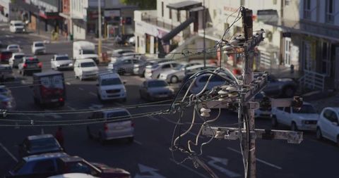 Tangled utility pole carrying power lines above busy downtown intersection and traffic