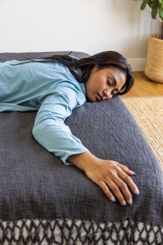 Asian woman reclining on gray sofa in cozy minimalist living room, resting