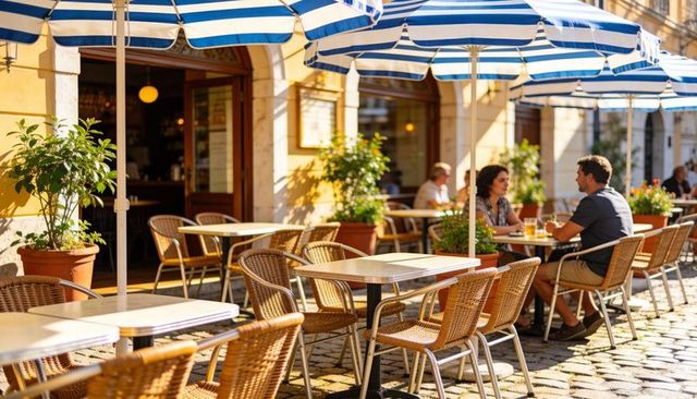 Couple chatting and sipping drinks at sunlit cafe patio with blue striped umbrellas