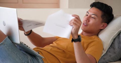 Young man reviewing documents while working leisurely at home
