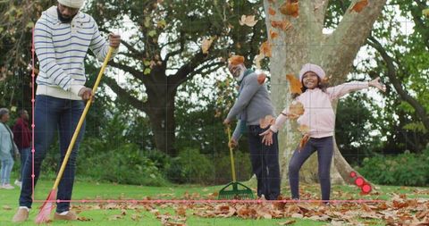 Multigenerational family raking leaves with child joyfully tossing autumn foliage in park