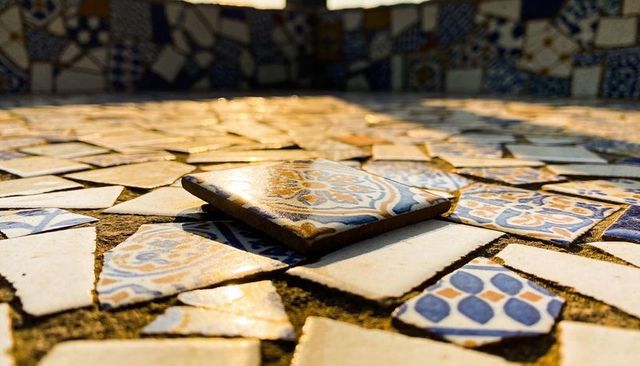 Sunlit blue-orange mosaic tile reflecting warm golden glow on courtyard bench