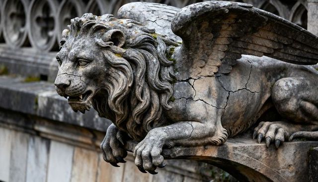 Weathered winged lion sculpture with cracked stone, moss patina on ornate carved ledge