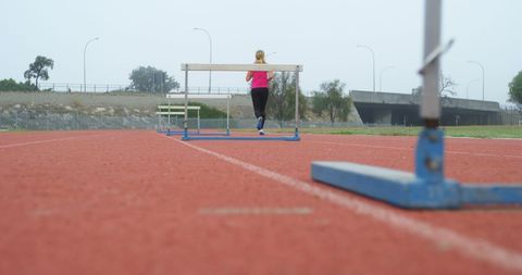 Female Athlete Preparing for Hurdles on Track - Download Free Stock Images Pikwizard.com