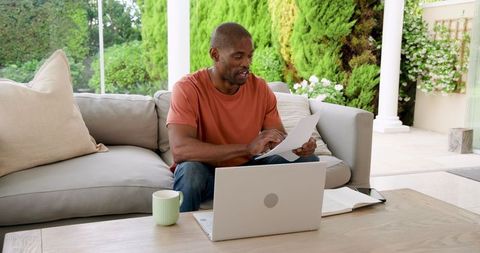 Man engaging in remote work from home with laptop and documents