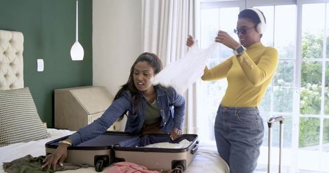 Diverse Friends Packing Suitcase in Bright Room