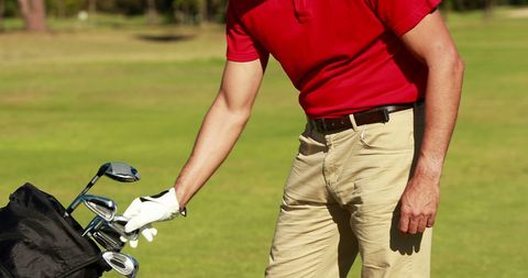 Male Golfer Choosing Club from Golf Bag on Sunny Course