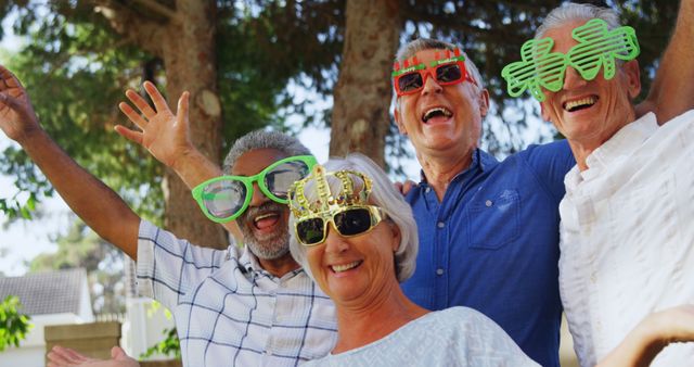 Group of senior friends having a good time outdoors, showcasing togetherness and fun, wearing quirky novelty glasses. Perfect for senior living communities, showing active lifestyles, advertisements for social events or parties, and promoting friendship among older adults.