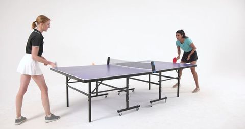 Female Athletes Competing in Intense Table Tennis Match