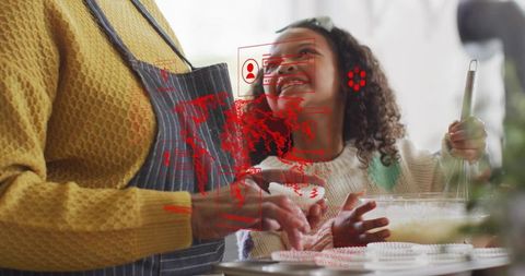 Senior Woman Guiding Child Baking Cupcakes with Augmented Reality Overlay in Kitchen