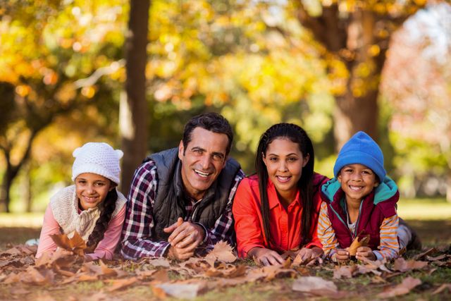 Portrait of cheerful family lying on field at park during autumn