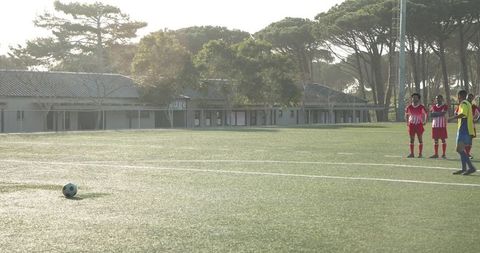 Young Footballer Practicing Free Kick on School Field Outdoors
