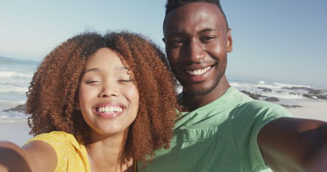Portrait of happy biracial couple standing on beach and smiling. Summer, relaxation, vacation, happy time, summer time, romance.