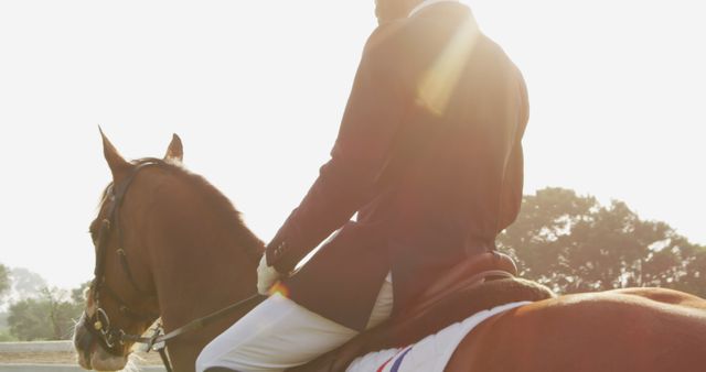 Photo capturing an equestrian rider on horseback at sunset. Rider dressed in formal equestrian attire. Ideal for themes such as equestrian sports, outdoor activities, competitions, horsemanship manuals, and leisure sports content.