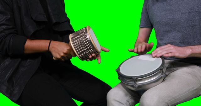 Mid section of musicians playing cabasa and drum against green screen