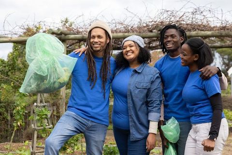 African american volunteers smiling while working community garden and collecting produce