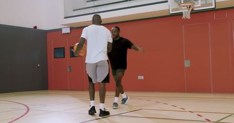 African american men practicing basketball drills and shaking hands on indoor court