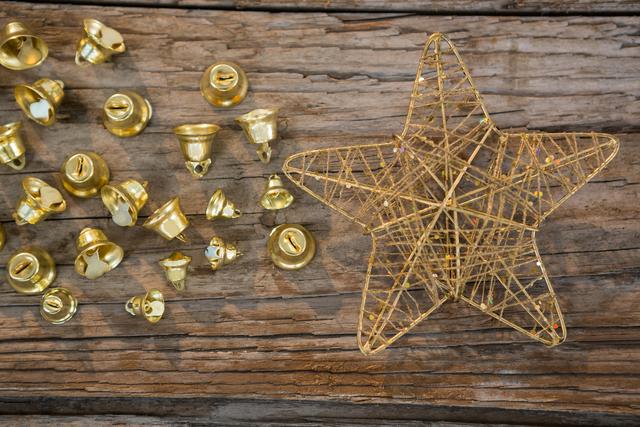 Golden Christmas bells and a star placed on a rustic wooden plank. Ideal for holiday-themed designs, greeting cards, festive advertisements, and seasonal blog posts. Perfect for adding a touch of traditional holiday charm to any project.