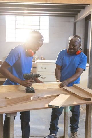 African american carpenters collaborating on woodworking project in bright workshop