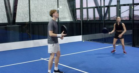 Couple enjoying padel tennis match on blue synthetic court