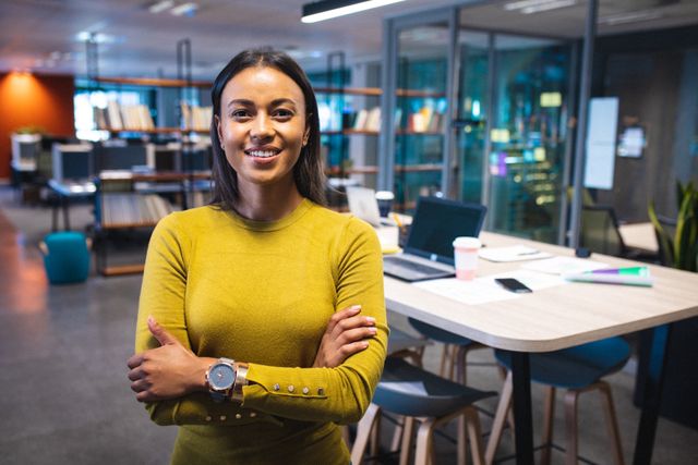 Young Asian businesswoman confidently standing with arms crossed in a modern office. Ideal for use in corporate websites, business presentations, career development materials, and professional networking profiles.