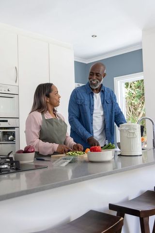 Mature black couple preparing healthy meal together in bright modern kitchen