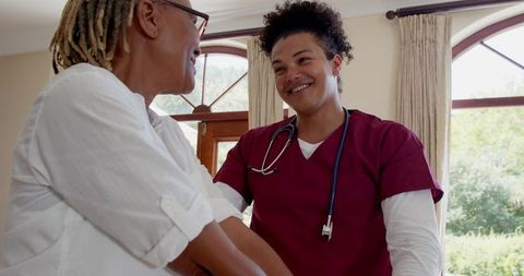 Compassionate nurse assisting african american senior woman at home