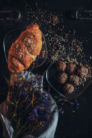 Rustic croissant and chocolate truffles with flowers on black