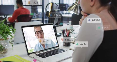 Businesswoman watching remote video call on laptop with social media notification overlays