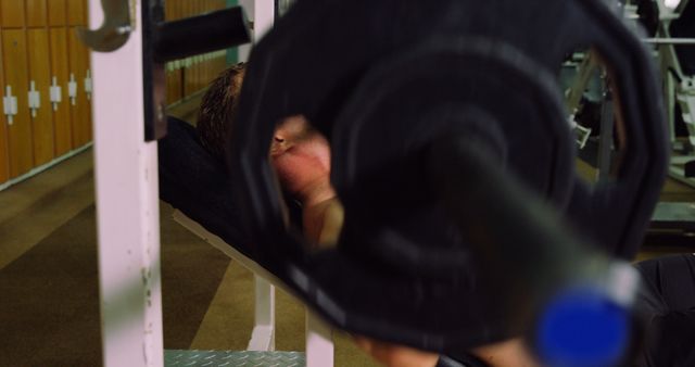 Man exercising by lifting weights on a bench press machine in a gym. This image is ideal for fitness, health, lifestyle, and strength training related content, showcasing dedication and physical health improvement.