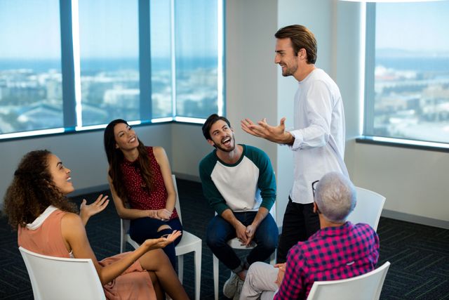 Group of diverse business professionals engaging in a lively discussion in a modern office environment. Ideal for use in articles or presentations about teamwork, collaboration, corporate culture, creative brainstorming sessions, and professional interactions.