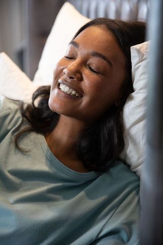 Asian Woman Smiling Relaxing on Comfortable Bed with White Pillow
