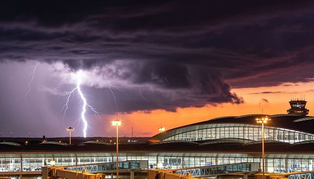 Lightning striking airport terminal at dusk with dramatic shelf cloud and illuminated control tower