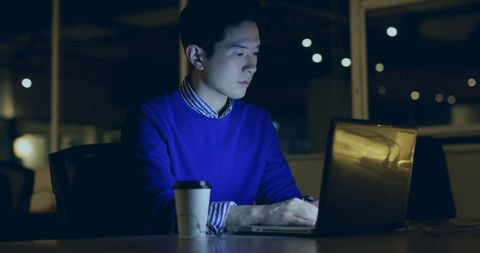 Focused Man Working Late Night in Office Using Laptop