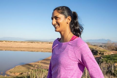Smiling woman in pink athletic top by scenic reservoir