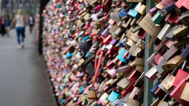 Close-up view of a fence crowded with colorful love locks symbolizing romance and commitment. Ideal for content related to love traditions, urban landscape, Valentine's Day, travel destinations, or community bonds.