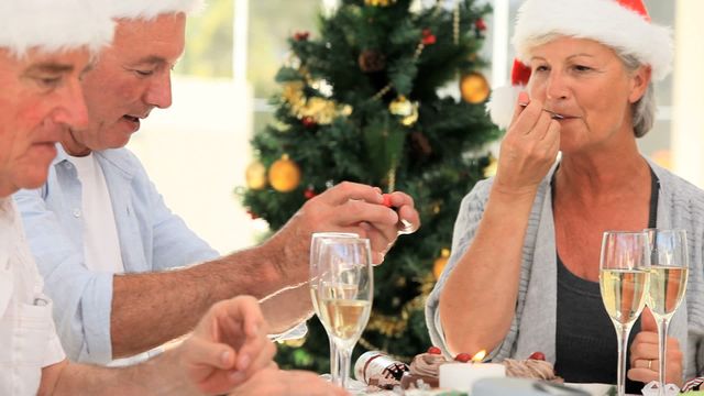 Elderly friends enjoying cake and drinks at a festive gathering during the holiday season. This video is suitable for advertisements or promotions related to holiday celebrations, senior communities, family gatherings, or festive events.