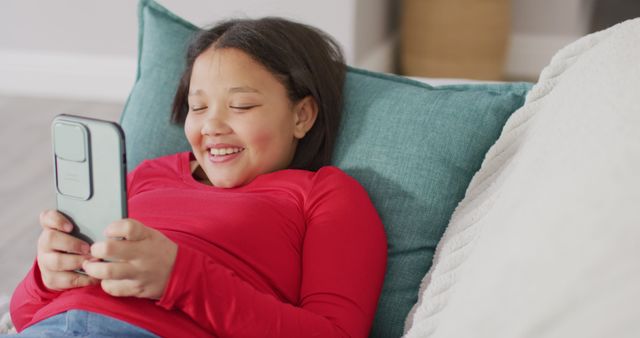 Image of happy asian girl resting on sofa with smartphone - Download Free Stock Photos Pikwizard.com