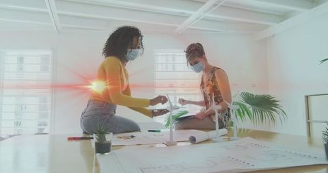 Businesswomen Collaborating on Project While Wearing Masks in Office