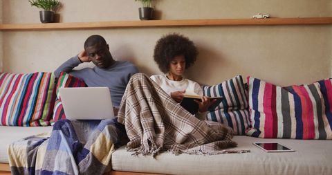 Couple Relaxing on Sofa with Laptop and Book