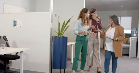 Team of colleagues discussing projects walking office corridor