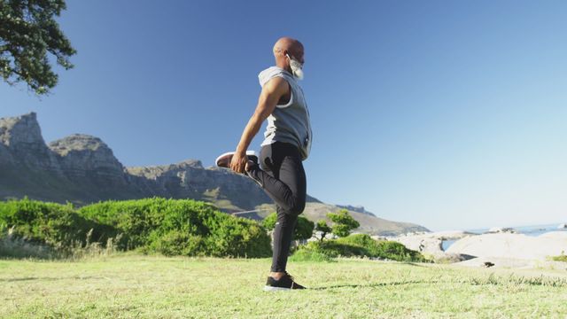 This video showcases a senior African American man performing a stretching exercise near a scenic seaside coast during a sunny day. Ideal for use in promoting health and fitness for seniors, blog posts on active retirement lifestyles, wellness campaigns, and outdoor fitness routines.