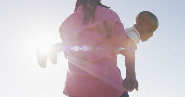 Silhouetted Parent Carrying Child with Sunburst in Background - Download Free Stock Images Pikwizard.com