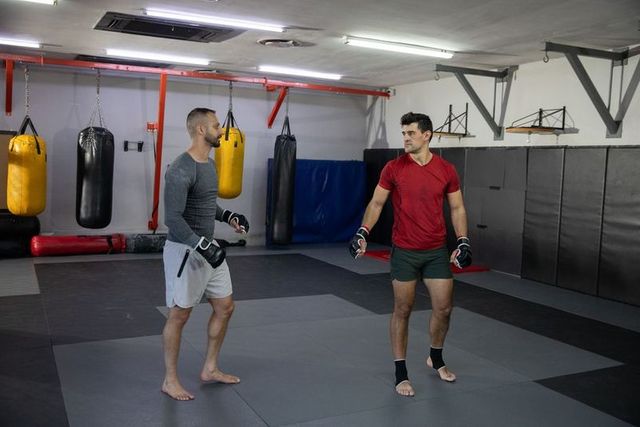 Male mma sparring partners training barefoot on mats in modern martial arts gym