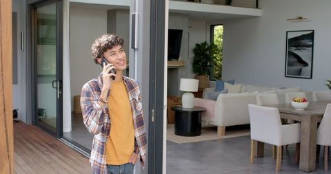 Man talking on smartphone on modern patio with interior view