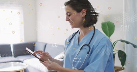 Medical Professional in Scrubs Using Digital Tablet in Lounge